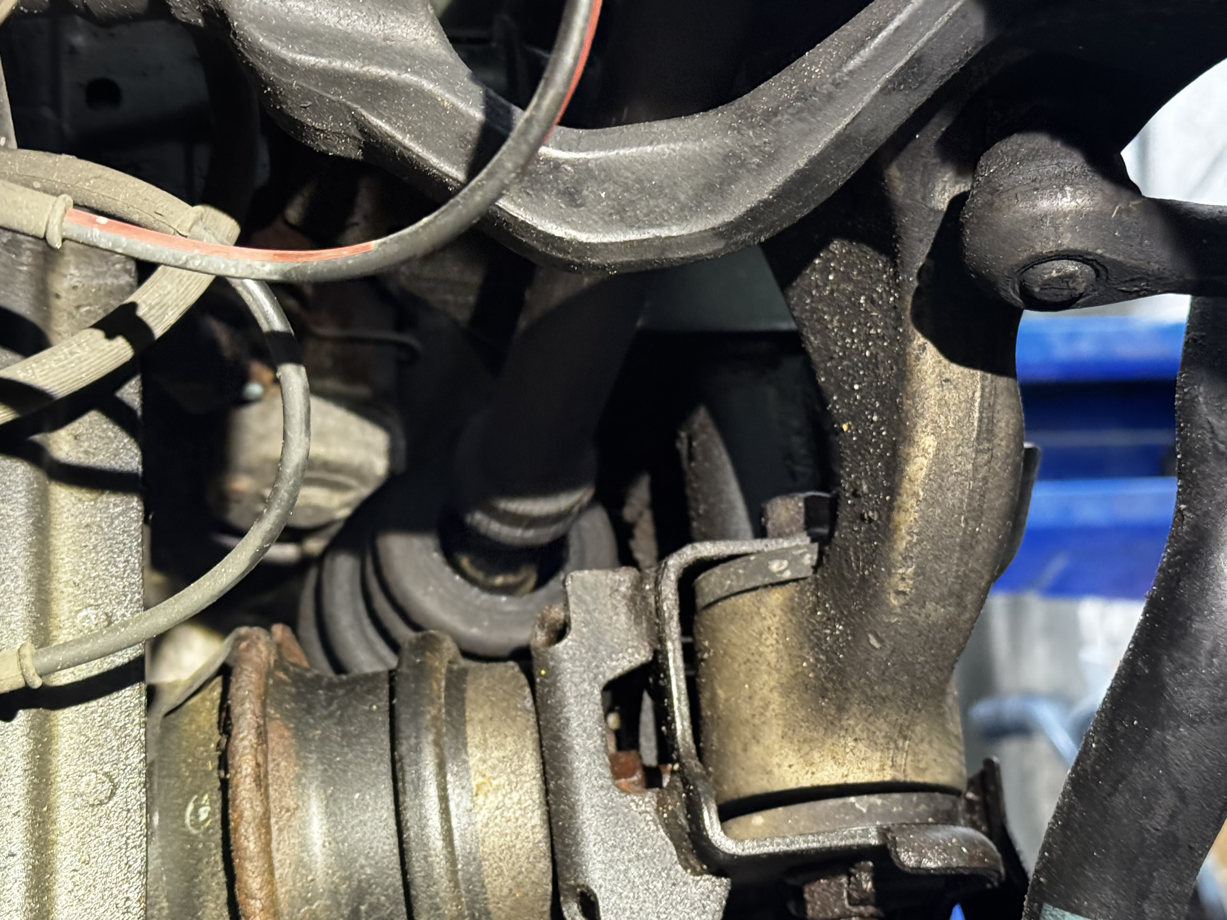 Undercarriage of 2010 Infiniti G37x on the lift at BR Prestige Auto Atlanta — showing worn drive side CV axle and control arm prior to replacement